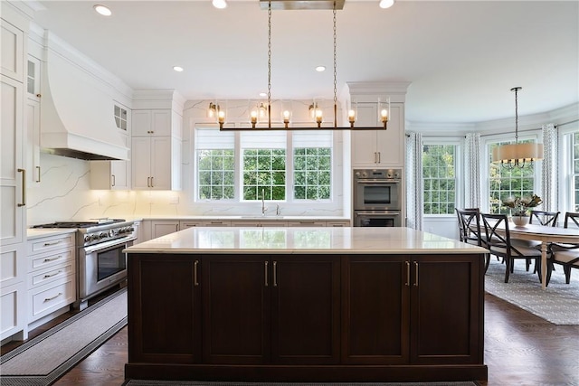 kitchen featuring a chandelier, glass insert cabinets, a center island, stainless steel appliances, and white cabinetry