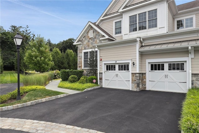 view of home's exterior with stone siding, aphalt driveway, and an attached garage