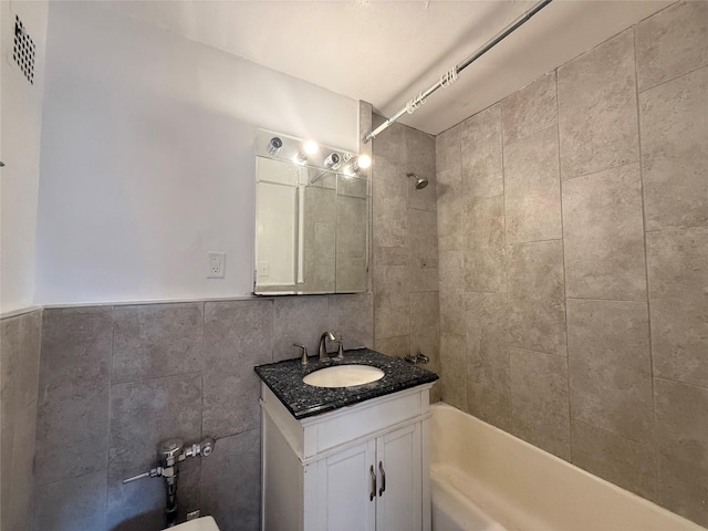 bathroom featuring tile walls, bathtub / shower combination, and vanity