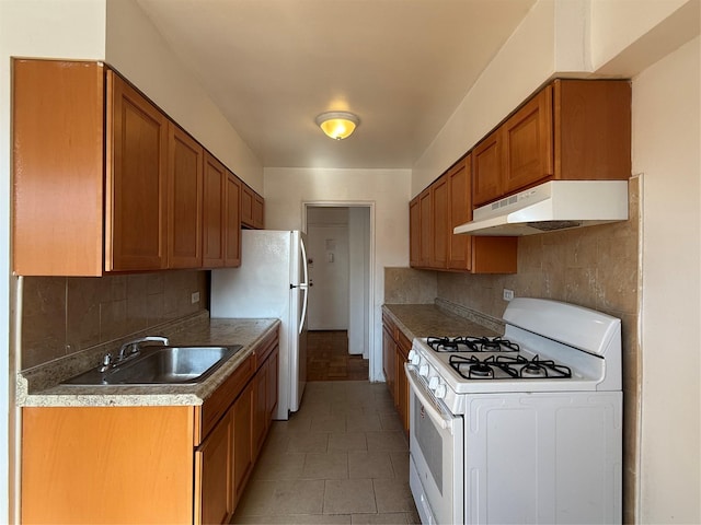 kitchen with tasteful backsplash, white appliances, a sink, and under cabinet range hood