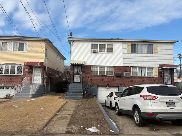 multi unit property featuring brick siding, driveway, and an attached garage