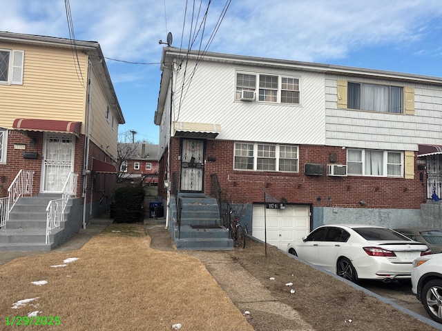 view of property featuring an attached garage, cooling unit, and brick siding