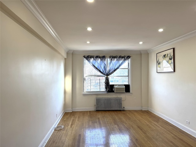 empty room featuring radiator, baseboards, crown molding, and hardwood / wood-style floors