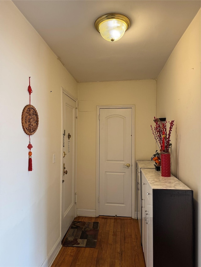 corridor with baseboards and dark wood-style flooring