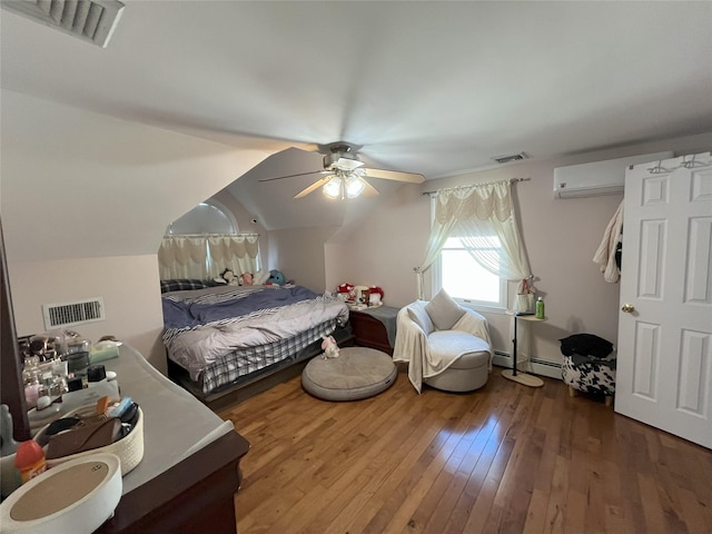 bedroom with lofted ceiling, hardwood / wood-style floors, visible vents, and an AC wall unit