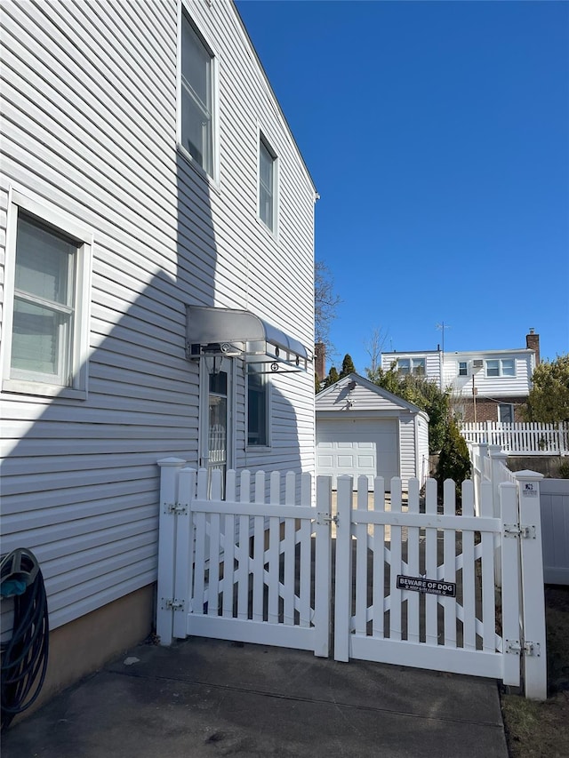 view of home's exterior featuring a garage, a gate, fence, and an outdoor structure