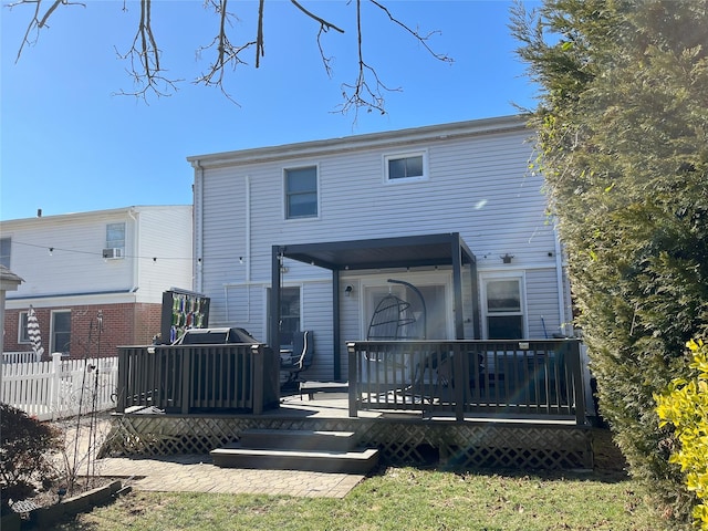 rear view of house featuring fence and a deck