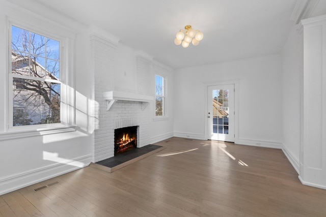 unfurnished living room featuring visible vents, a fireplace, baseboards, and wood finished floors