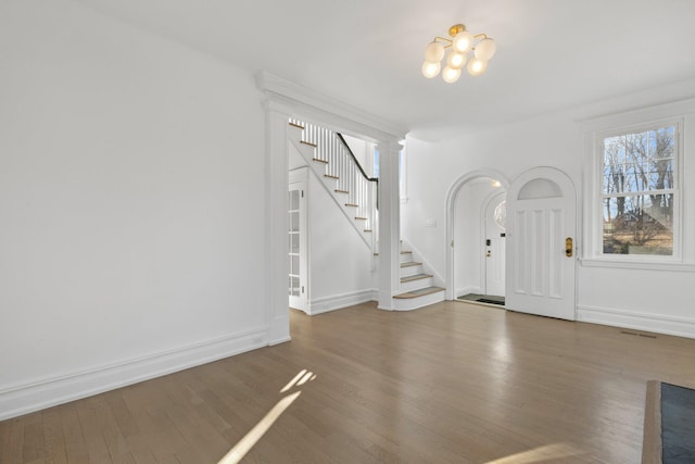 entryway with wood finished floors, baseboards, an inviting chandelier, and stairs