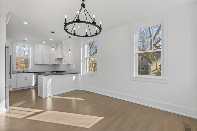 kitchen featuring dark countertops, wood finished floors, premium range hood, white cabinetry, and backsplash