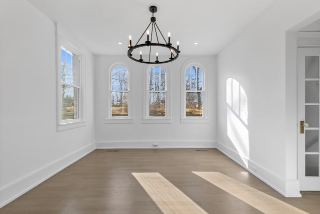 unfurnished dining area featuring a chandelier, recessed lighting, baseboards, and wood finished floors