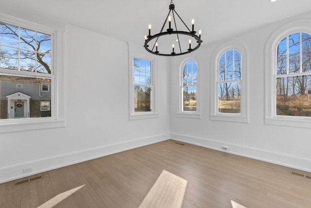 unfurnished dining area featuring a wealth of natural light, visible vents, and wood finished floors