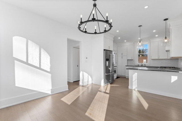 kitchen with tasteful backsplash, high end fridge, white cabinets, and light wood-style flooring