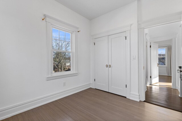 unfurnished bedroom featuring a closet, wood finished floors, and baseboards