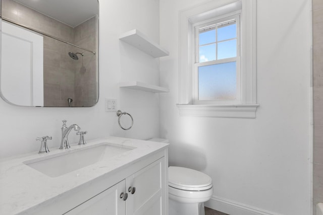 bathroom with a shower, baseboards, vanity, and toilet