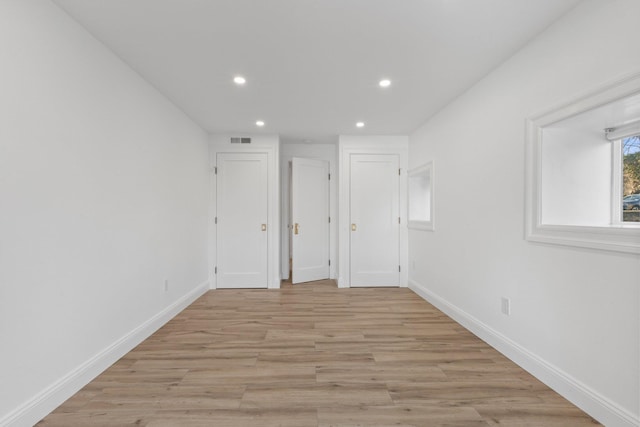 empty room featuring light wood-style floors, visible vents, and baseboards