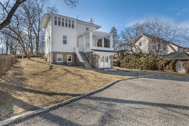 view of front of home with a chimney, stairway, a pergola, stone siding, and a front lawn