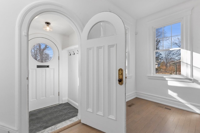 entryway with wood finished floors, visible vents, and baseboards