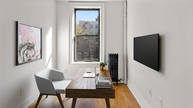 home office with radiator heating unit, wood finished floors, and baseboards