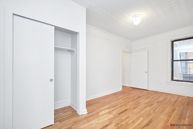 unfurnished bedroom featuring an ornate ceiling, light wood-type flooring, and baseboards