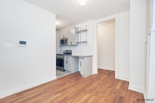 kitchen featuring light wood-style flooring, stainless steel appliances, light countertops, open shelves, and tasteful backsplash