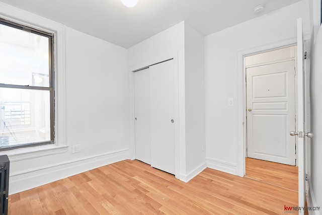 unfurnished bedroom with a closet, baseboards, and light wood finished floors