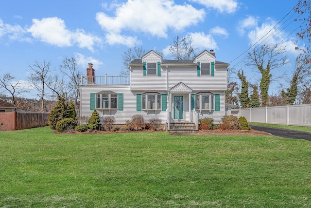 view of front of property featuring a chimney, a front yard, and fence