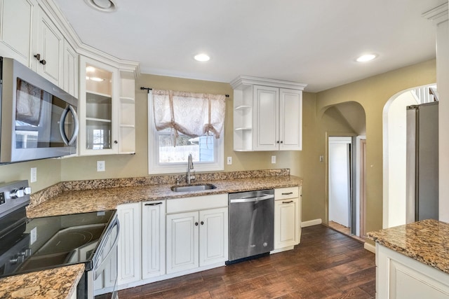 kitchen with dark wood-style floors, arched walkways, open shelves, stainless steel appliances, and a sink