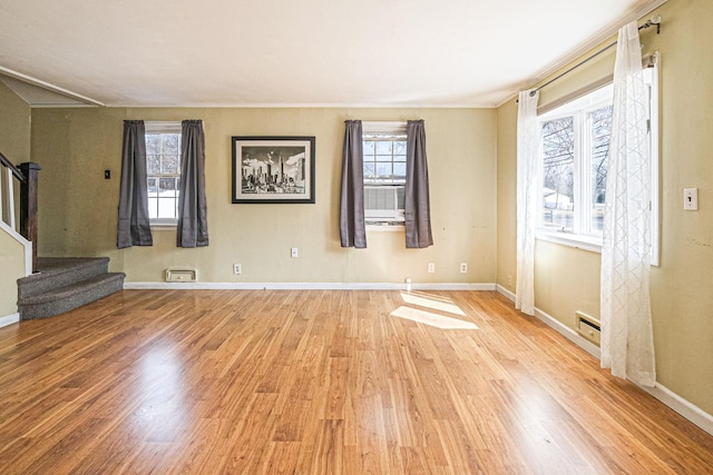 unfurnished living room with plenty of natural light, stairs, and wood finished floors