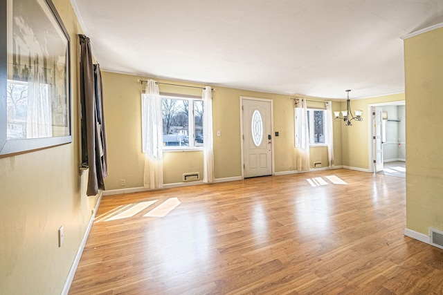 foyer entrance with baseboards, plenty of natural light, light wood-style flooring, and a notable chandelier