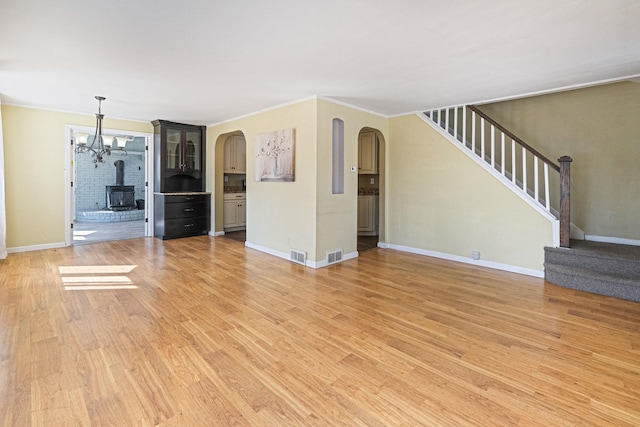 unfurnished living room with baseboards, visible vents, stairway, crown molding, and light wood-style floors