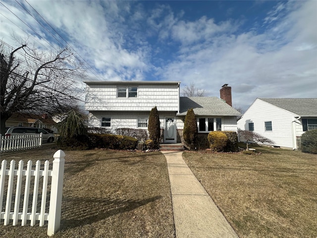 view of front of home with a shingled roof, a front lawn, and fence