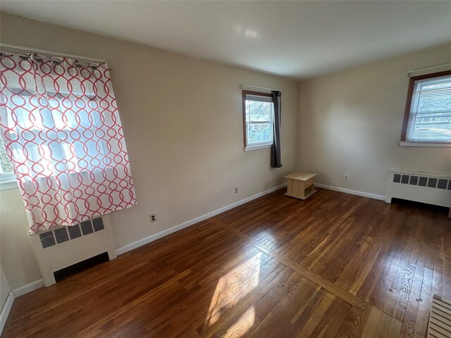 unfurnished room featuring radiator, baseboards, and hardwood / wood-style floors