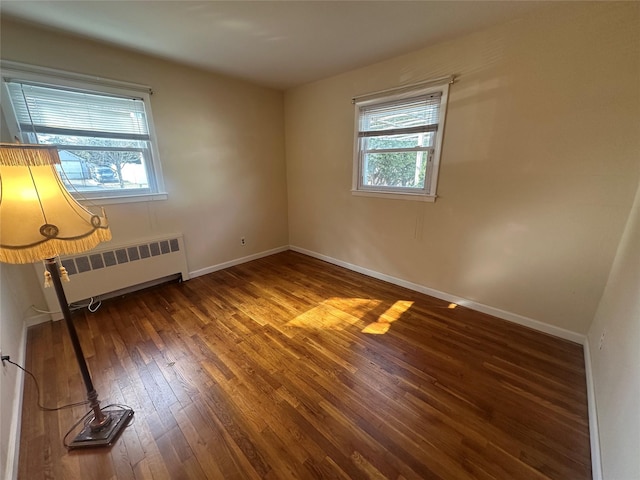 empty room with radiator heating unit, baseboards, and hardwood / wood-style floors