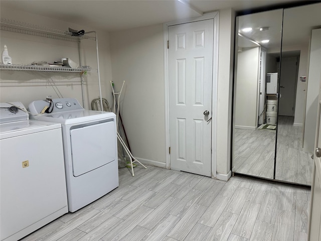 washroom with laundry area, wood finish floors, washer and clothes dryer, and baseboards