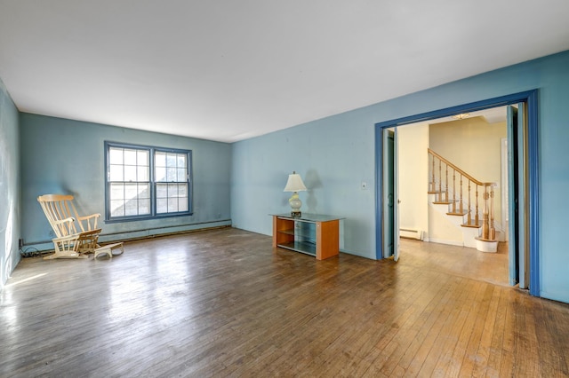 living room featuring a baseboard heating unit, stairway, and wood-type flooring