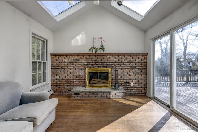 living area featuring a fireplace, high vaulted ceiling, a skylight, and wood finished floors