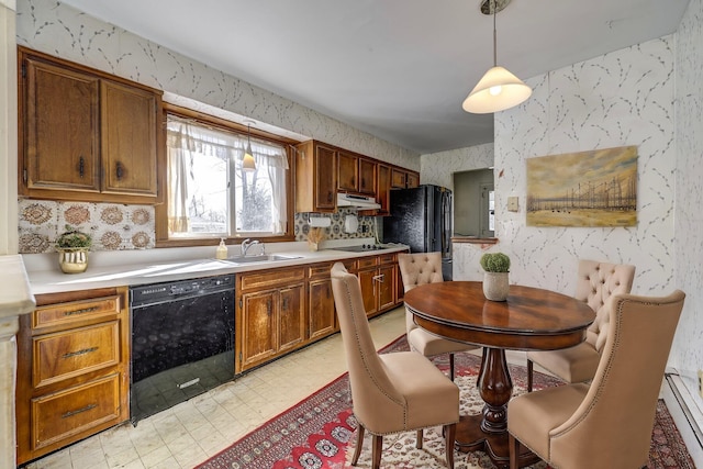 kitchen featuring under cabinet range hood, light countertops, black appliances, and wallpapered walls