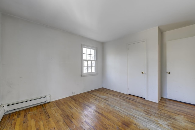 interior space featuring a baseboard heating unit and hardwood / wood-style flooring