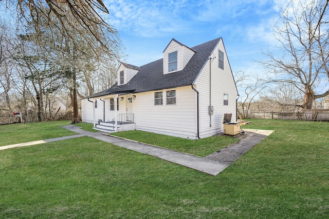 view of front of home with roof with shingles, fence, and a front yard