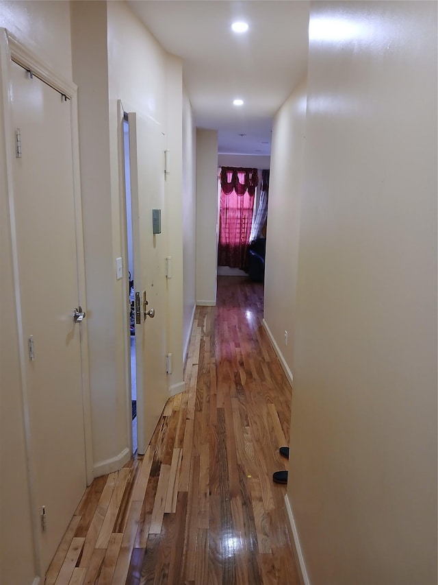 hall featuring baseboards, wood finished floors, and recessed lighting