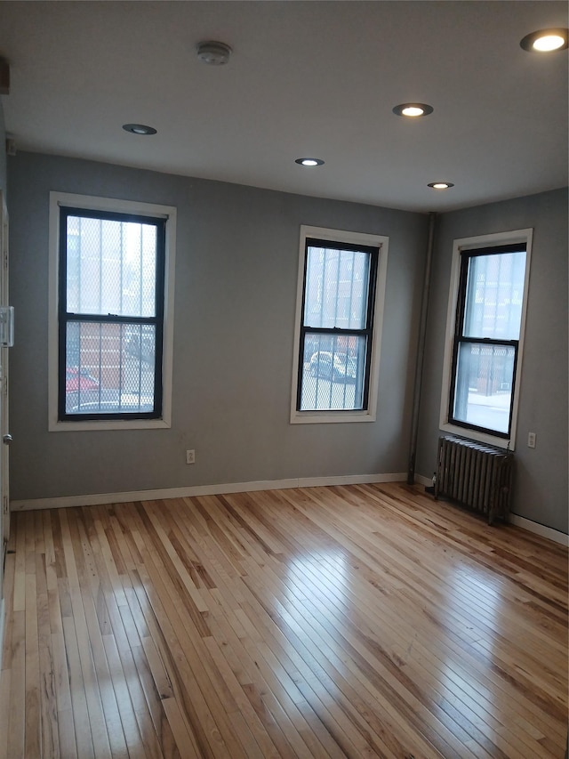 spare room with baseboards, hardwood / wood-style floors, recessed lighting, and radiator