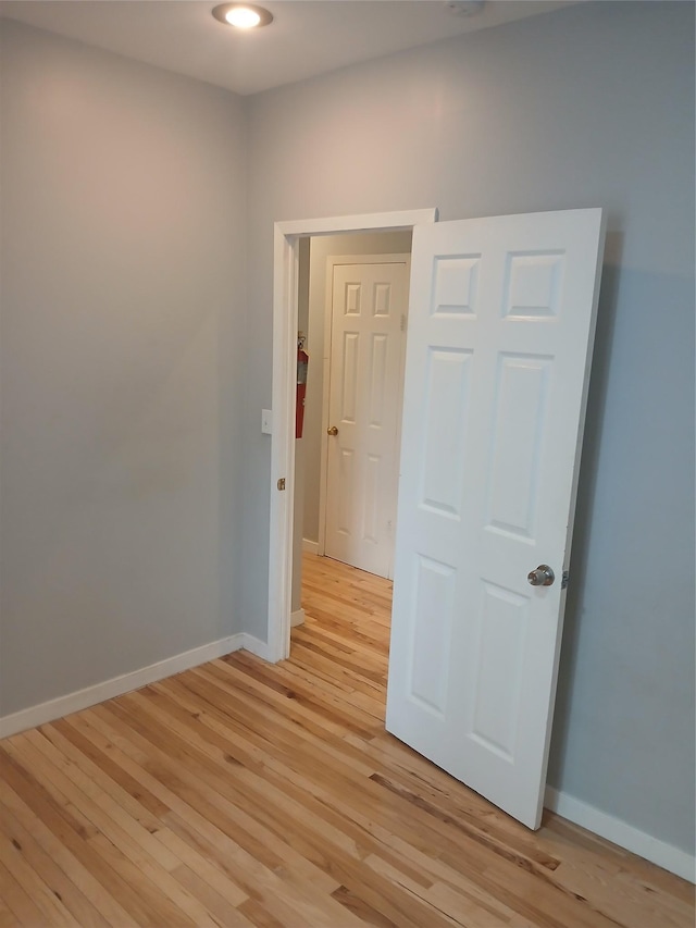 spare room with baseboards and light wood-style floors