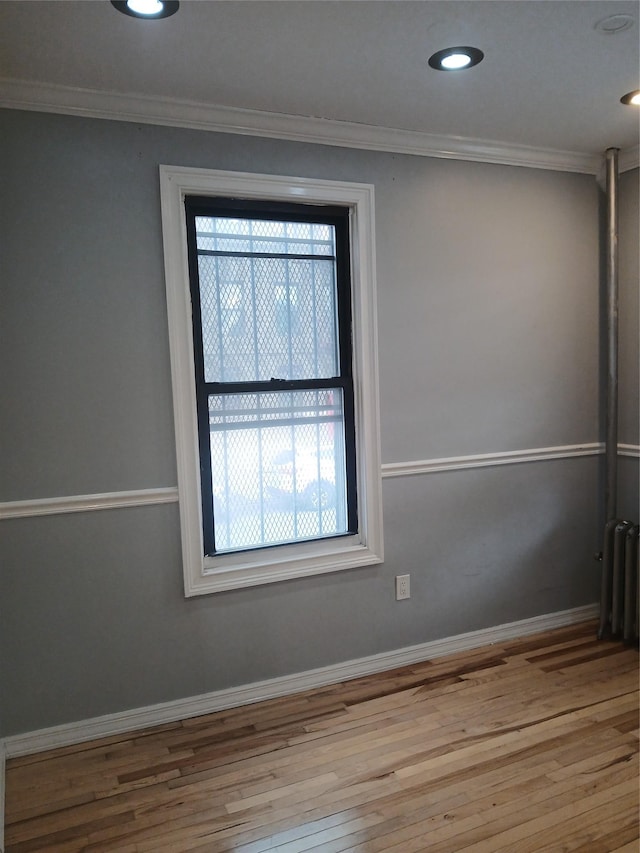 unfurnished room featuring radiator, a healthy amount of sunlight, and crown molding