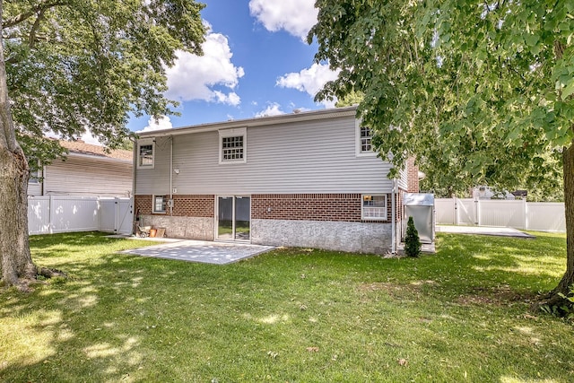 rear view of property featuring a patio, a lawn, and a fenced backyard