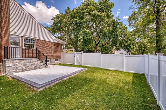 view of yard featuring a gate, a fenced backyard, and a patio