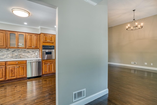 kitchen with brown cabinets, visible vents, backsplash, appliances with stainless steel finishes, and a sink