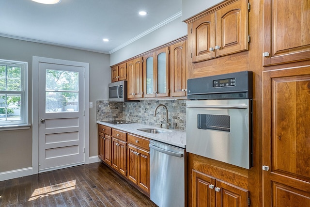 kitchen featuring appliances with stainless steel finishes, brown cabinetry, a sink, and ornamental molding