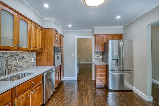 kitchen with stainless steel appliances, brown cabinetry, a sink, and dark wood-style flooring