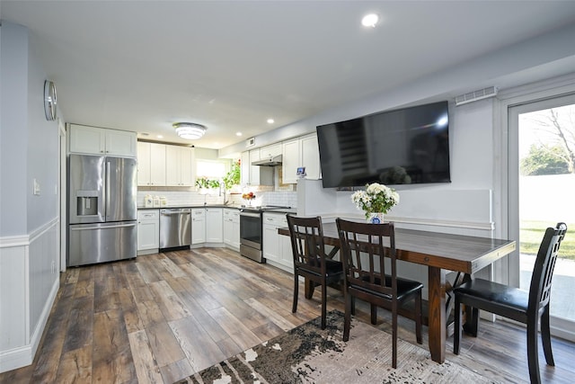 kitchen featuring visible vents, decorative backsplash, appliances with stainless steel finishes, dark wood-type flooring, and white cabinetry